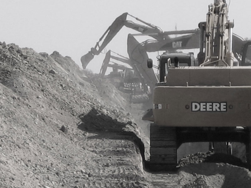 Pipeline installation with excavators lowering steel pipe into an open trench