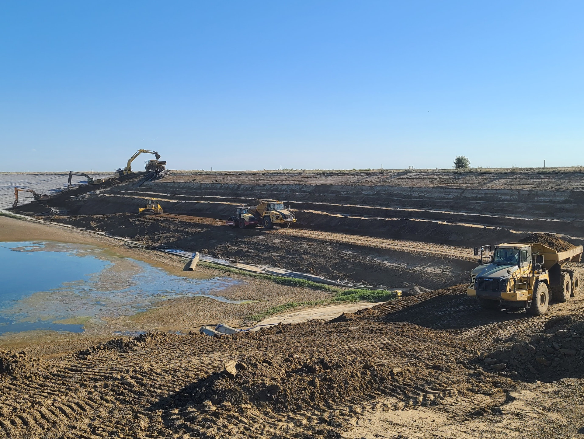 Large-scale earthworks and pond containment build with haul trucks